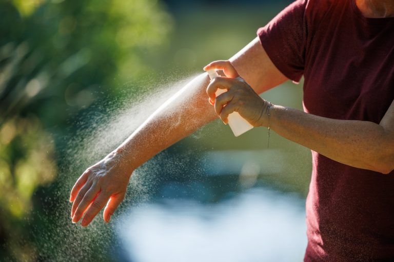 woman,applying,insect,repellent,on,her,arm,outdoors.,skin,protection